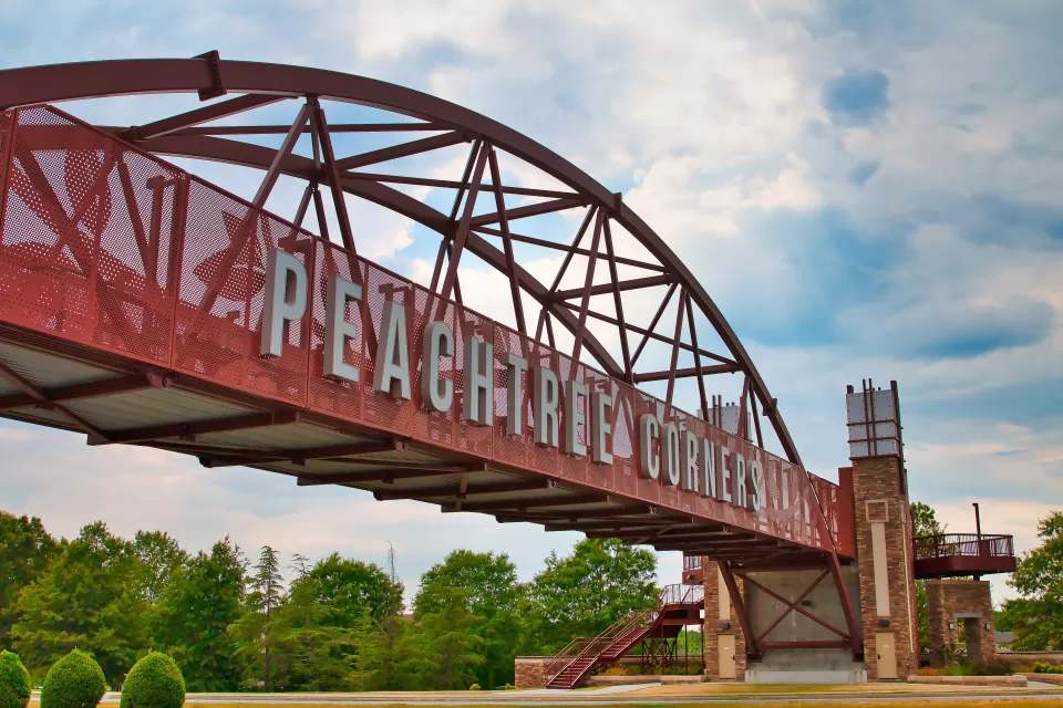 Red bridge with arches over highway with white letters spanning bridge "Peachtree Corners" near Atlanta, Georgia